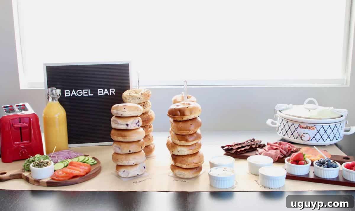 A wide shot of a bagel bar table setup, featuring multiple serving trays with bagels, cream cheeses, and fresh toppings.