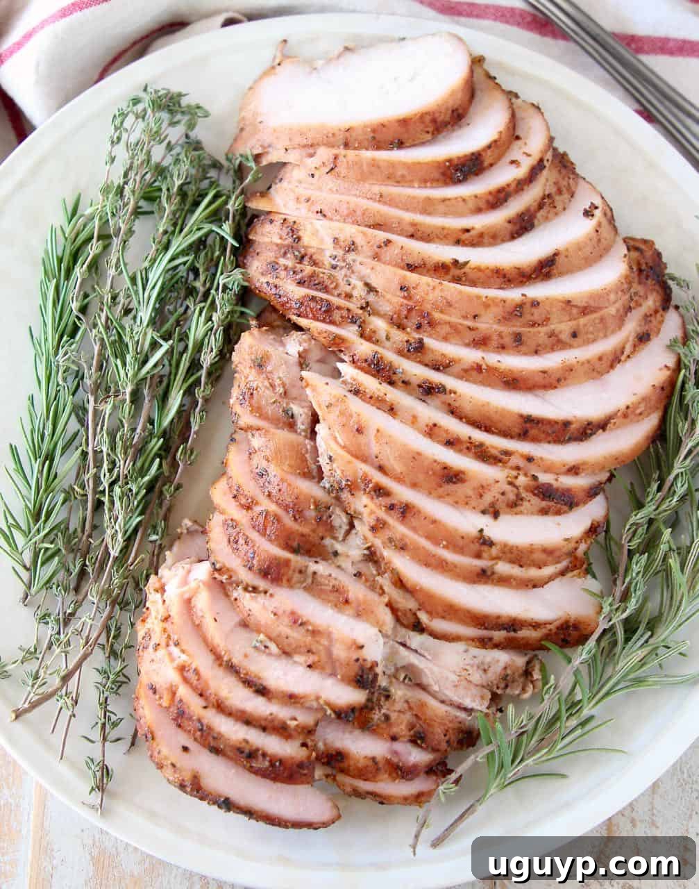 Slices of smoked turkey breast meat on plate with fresh herbs