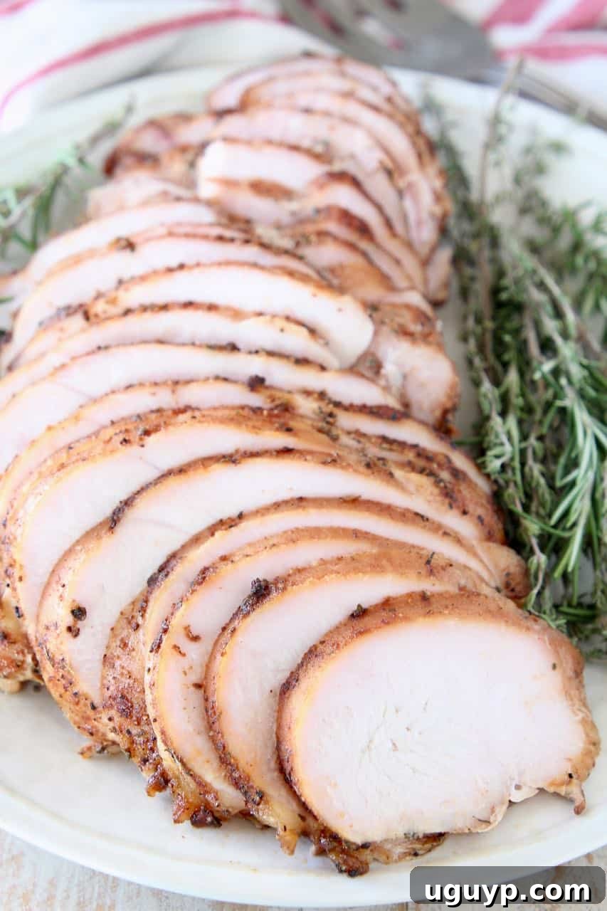 Sliced turkey breast on plate with fresh rosemary and thyme sprigs