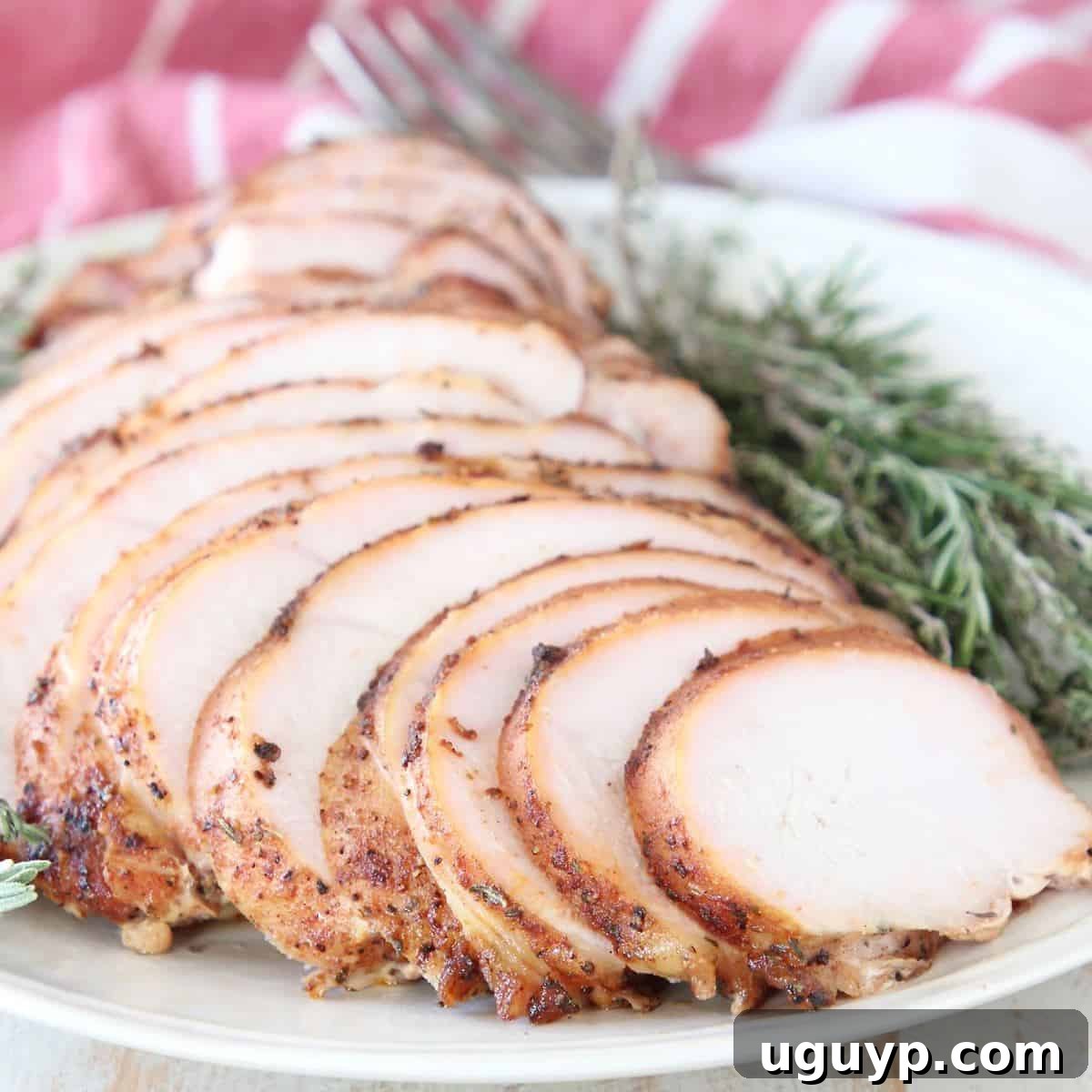 Sliced smoked turkey breast on plate with fresh rosemary and thyme