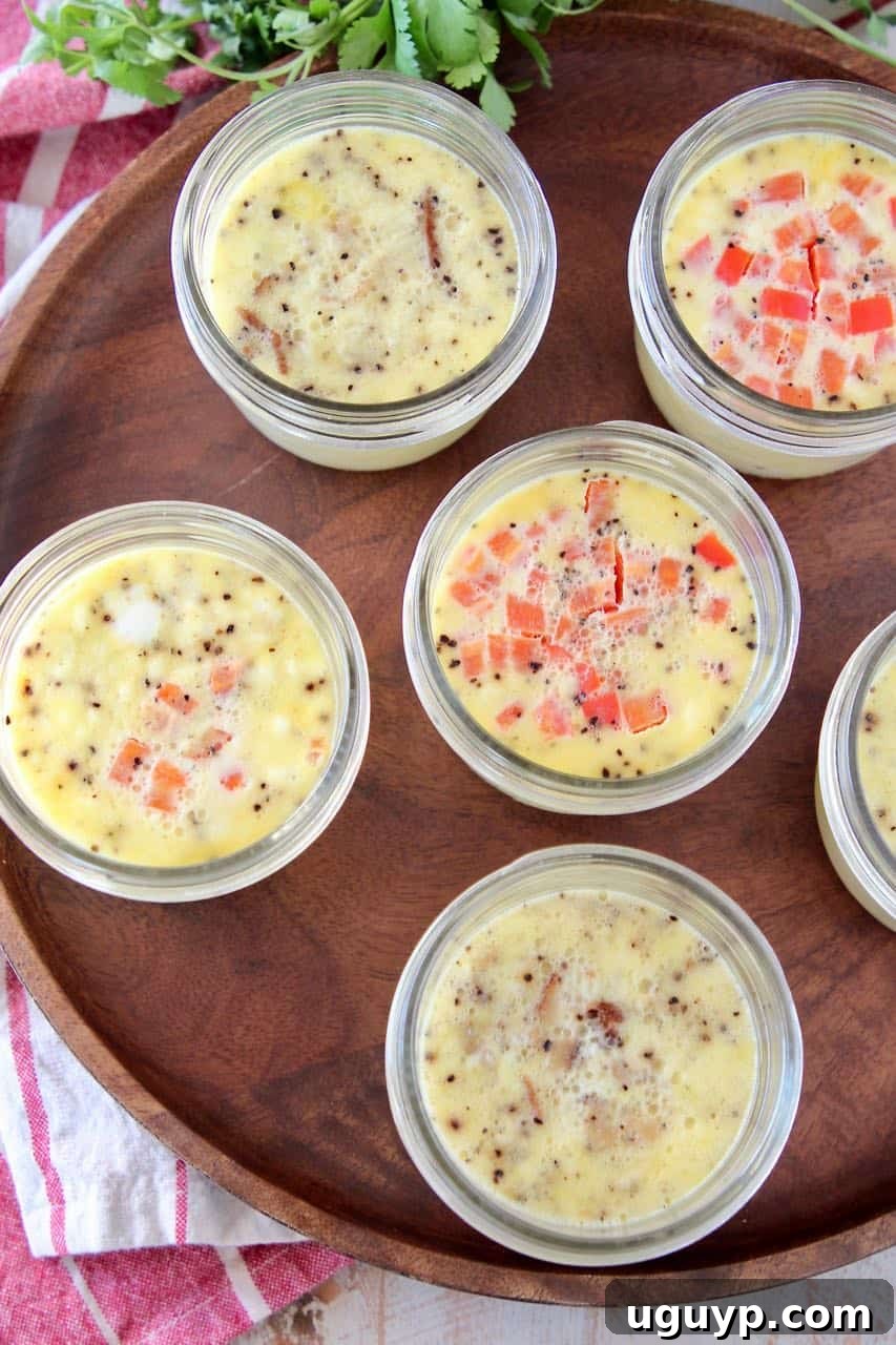 Homemade sous vide egg bites artfully arranged in mason jars on a rustic wood cutting board, ready to be enjoyed or stored.