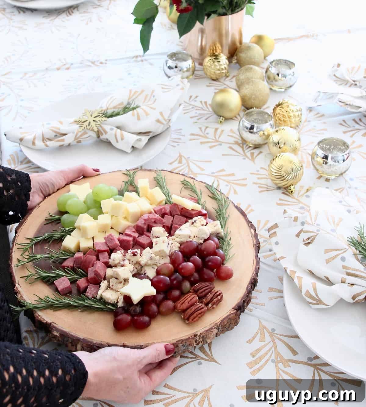 Hands holding Christmas tree holiday cheese board, showcasing festive holiday appetizer.