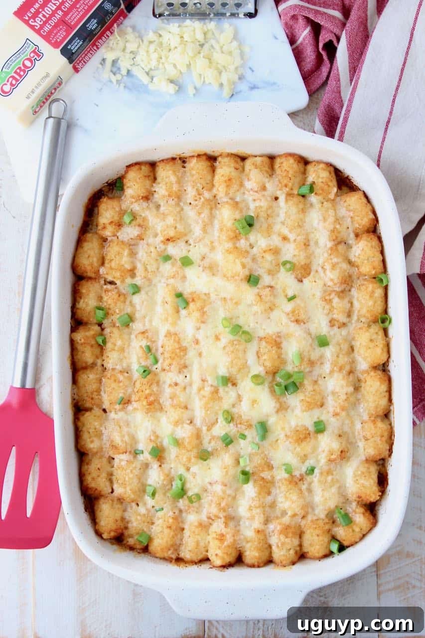 Breakfast tater tot casserole in casserole dish with red spatula on the side