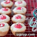 Sugar cookie cups with red frosting filling sitting on wire cooling rack