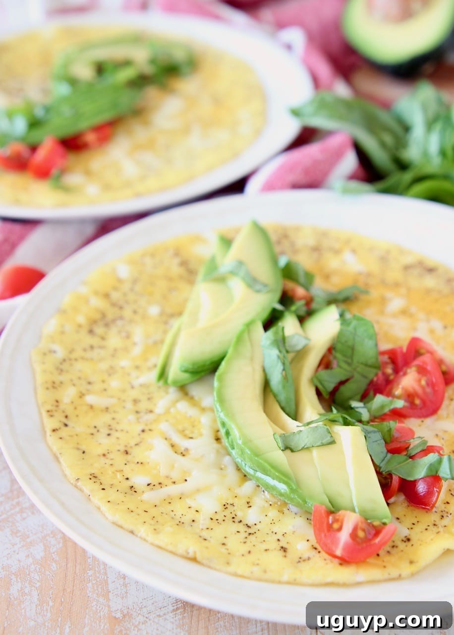 Avocado omelette with diced tomatoes and fresh basil on white plate. This 10-Minute Caprese Avocado Omelette is a healthy breakfast featuring avocado, tomatoes, mozzarella, and basil, and is vegetarian, gluten-free, and keto-friendly.