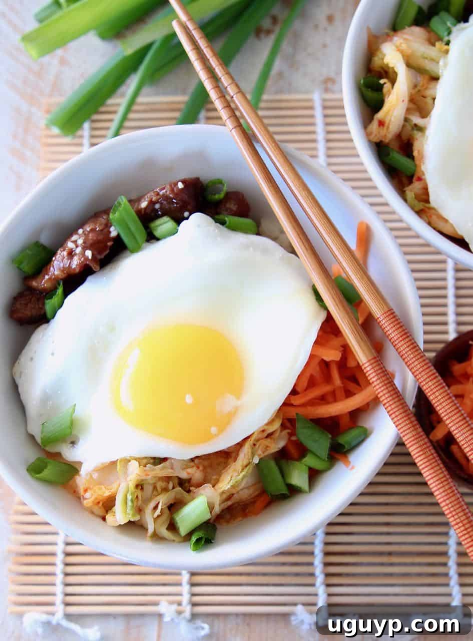 Korean BBQ Cauliflower Rice Bowl topped with a fried egg with chopsticks and green onions