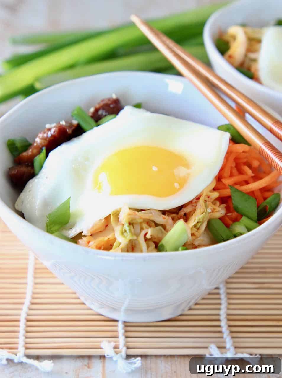 Korean BBQ Cauliflower Rice Bowl topped with a fried egg and chopsticks