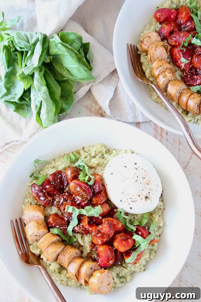 A beautifully presented bowl of creamy pesto risotto, garnished with savory sausage, vibrant roasted cherry tomatoes, and a generous portion of burrata cheese, highlighting the delicious texture and rich colors of the meal.