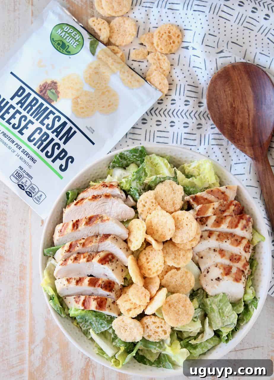 Healthy Chicken Caesar Salad in bowl topped with sliced grilled chicken and crispy parmesan crisps, ready to eat.