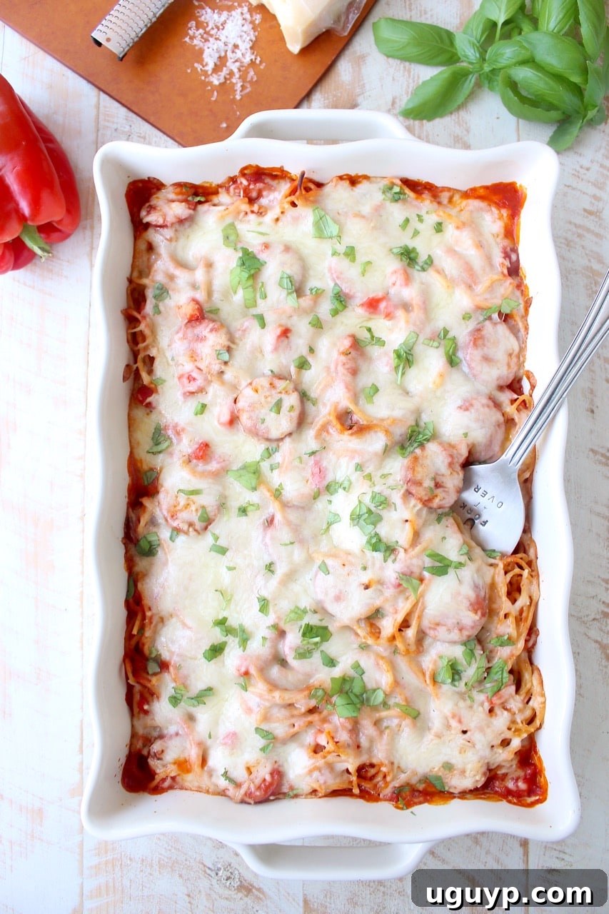 An easy Pizza Baked Spaghetti recipe featuring your favorite pizza toppings like sausage and peppers, tossed with spaghetti and pasta sauce, then topped with melted cheese.