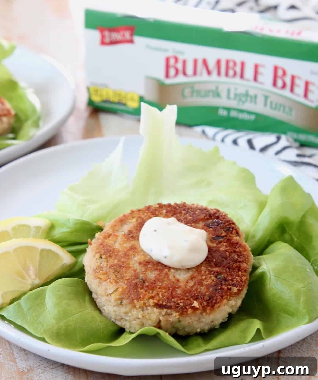 Crispy tuna patty on a leaf of butter lettuce, garnished with a lemon wedge, ready to be enjoyed.