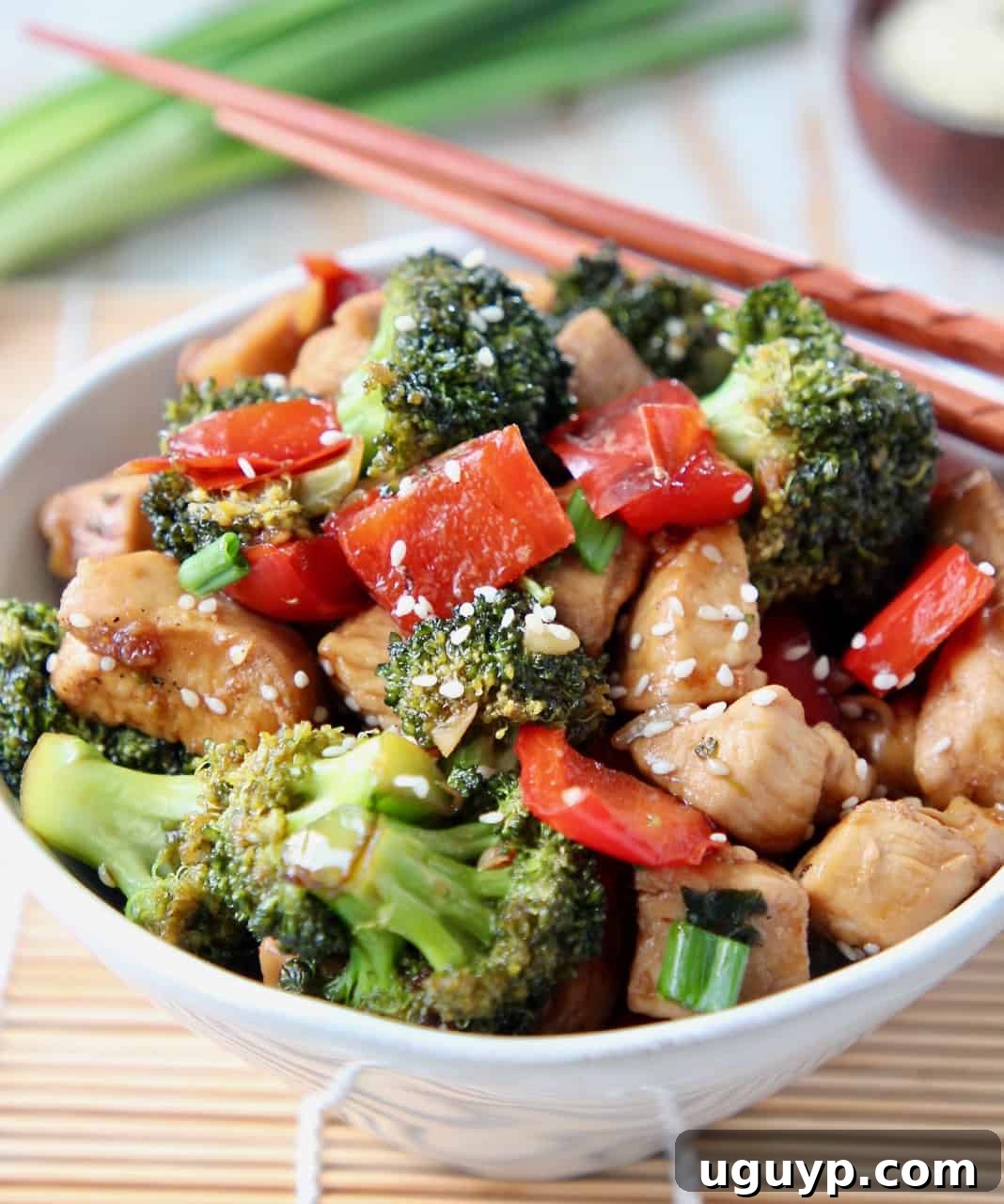 Stir fry teriyaki chicken and broccoli in white bowl with chopsticks on the side