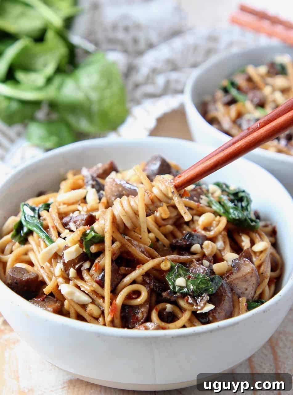 Chopsticks skillfully twirling noodles in a bowl, showcasing the delicious texture and generous coating of sauce.