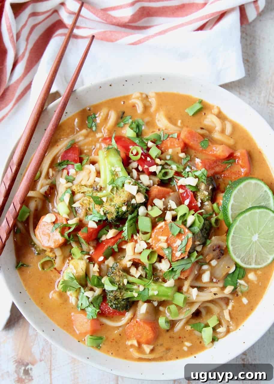 Overhead view of Massaman Curry noodles with vibrant vegetables and a rich sauce, served in a bowl with chopsticks on the side.