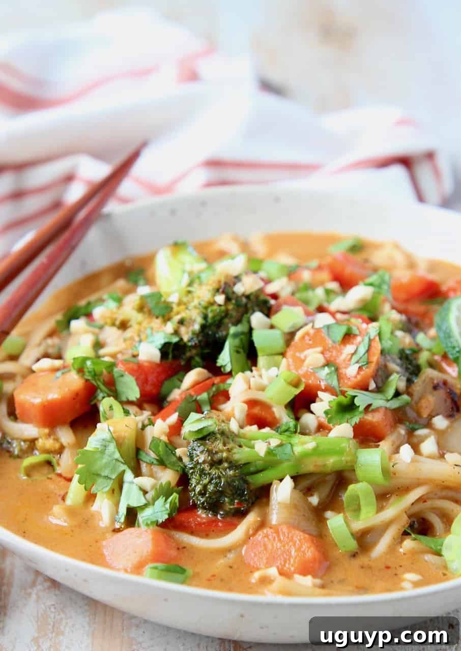 Close-up shot of vibrant vegetables simmering in a rich Massaman curry sauce in a bowl.