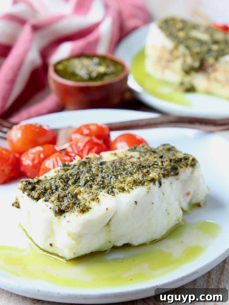 Chilean sea bass on plate topped with basil pesto, ready to be served