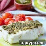 Sea bass covered in pesto on plate with cherry tomatoes and a fork
