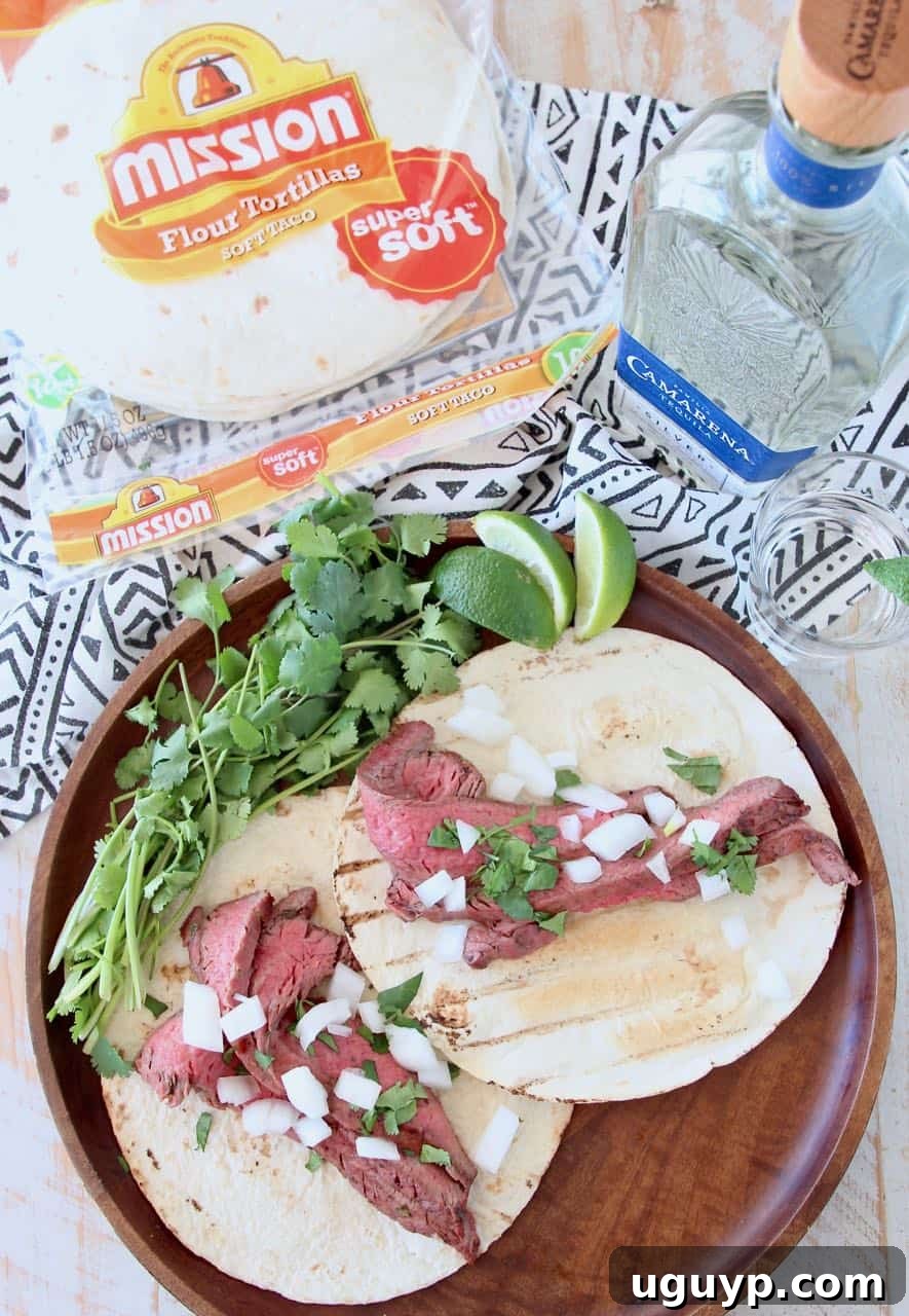 Grilled carne asada tacos garnished with fresh cilantro on a wooden tray