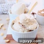 Scoops of peanut butter ice cream in white bowls with gold spoons