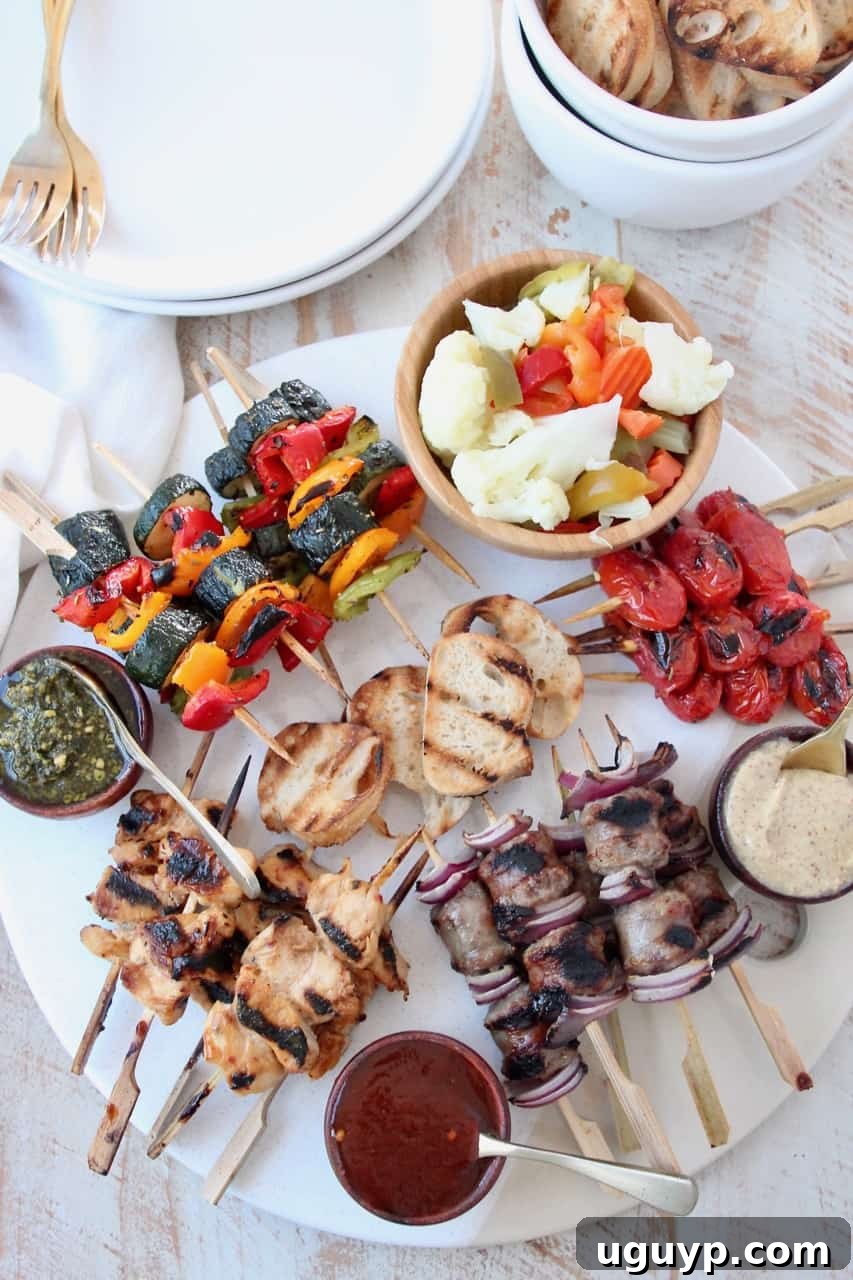 Overhead image of grilled mini skewers on charcuterie board with small bowls of sauces