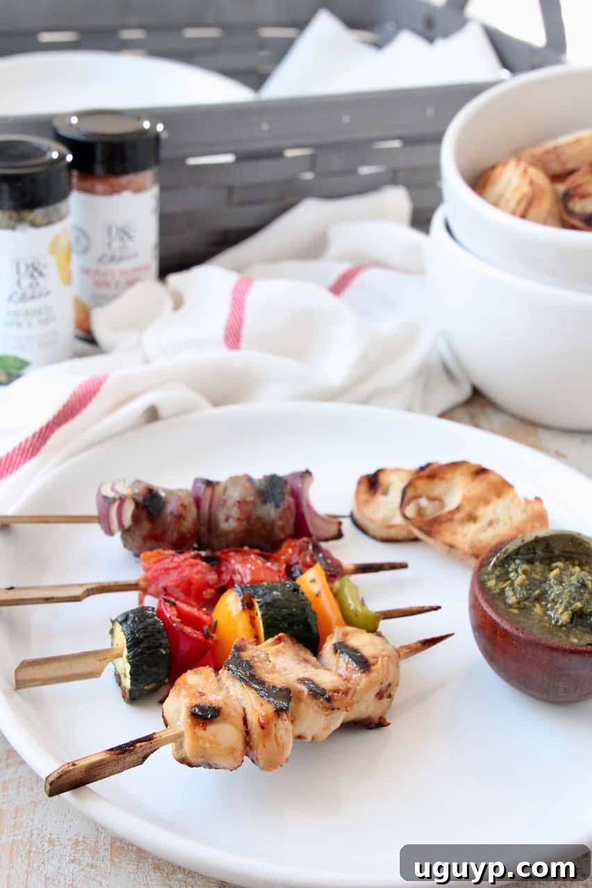 Grilled skewers on plate with small bowl of pesto and grilled slices of bread