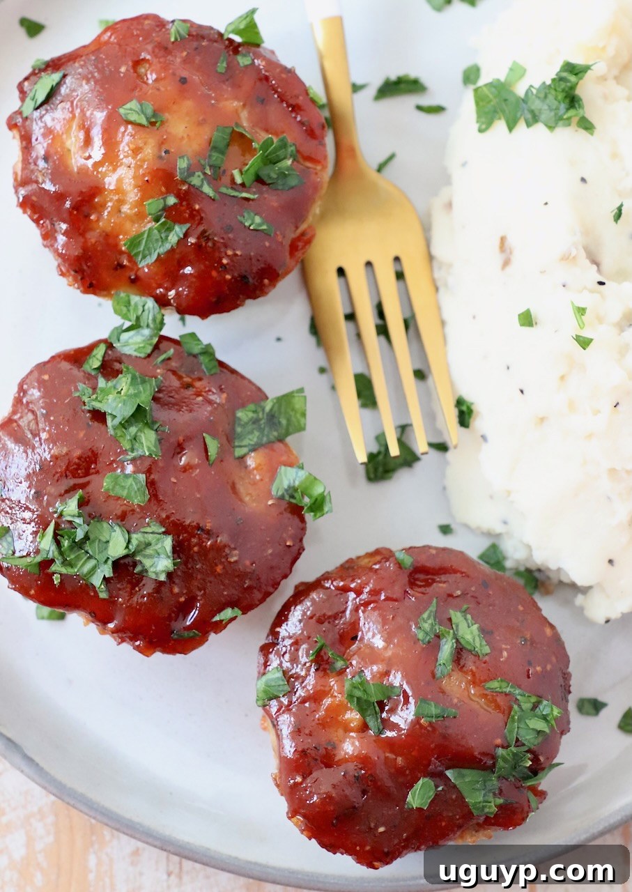Mini BBQ glazed meatloaves on a plate with fork and mashed potatoes