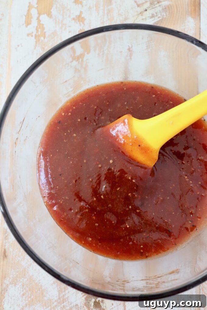 Homemade BBQ sauce mixed up in a small glass bowl with spatula
