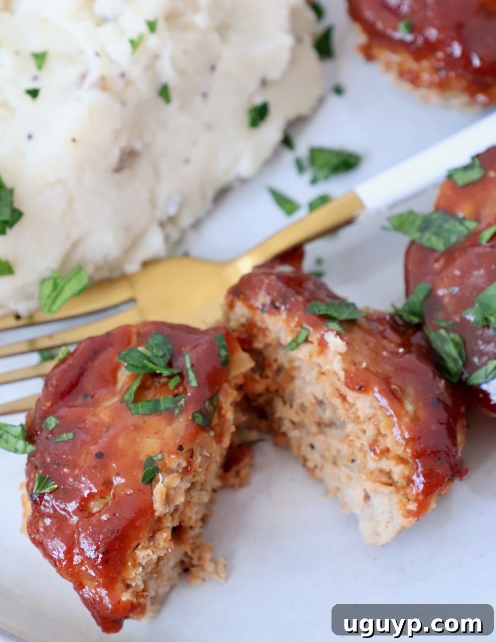 Mini meatloaf sliced in half on a plate with fork and mashed potatoes