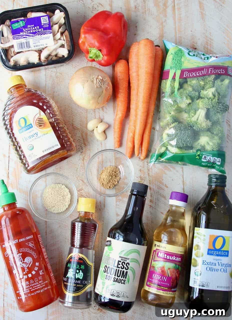 Overhead image showing a variety of fresh ingredients for roasted Asian vegetables laid out on a white surface