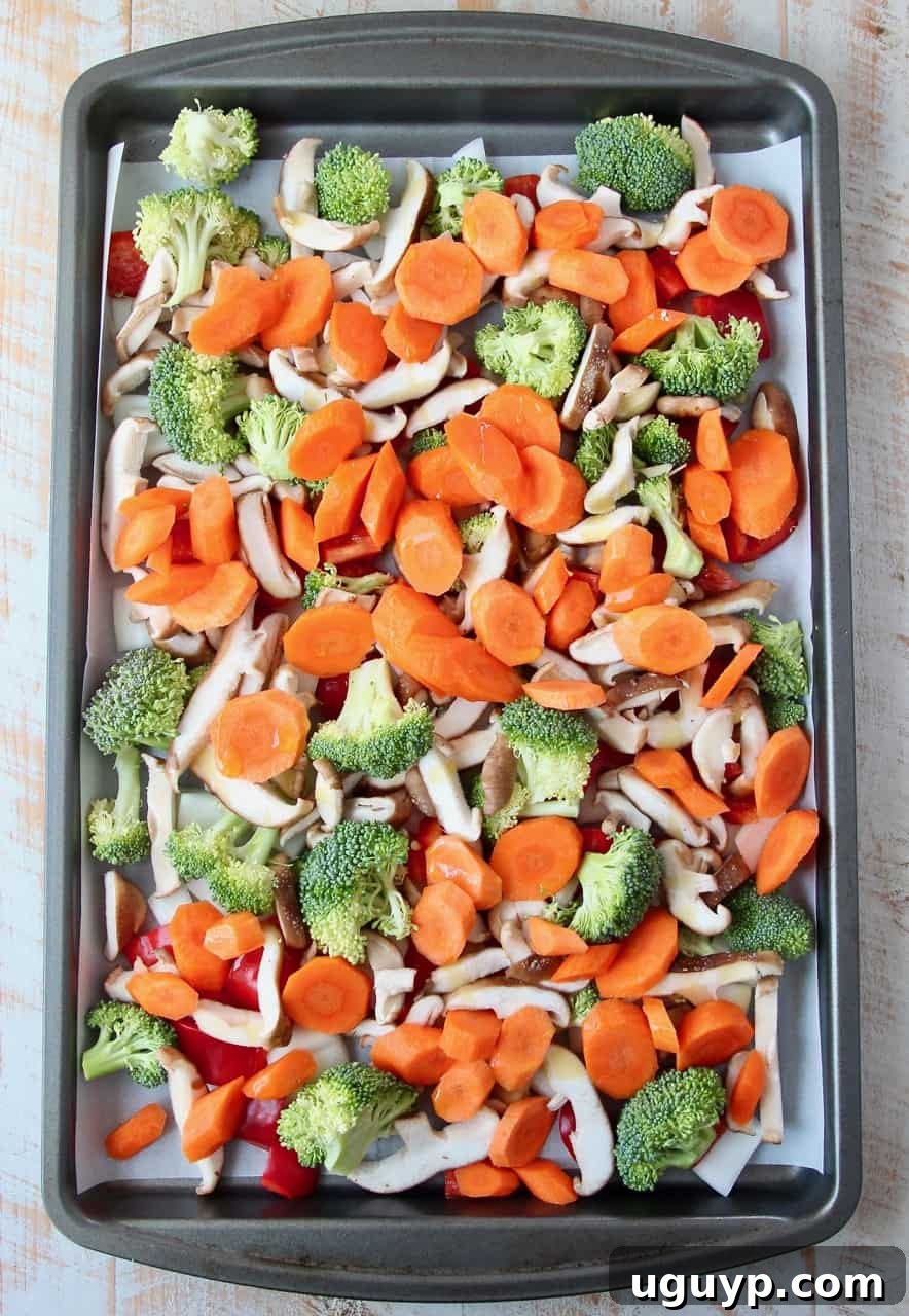 Overhead image of chopped vegetables spread on a baking sheet, ready for the oven
