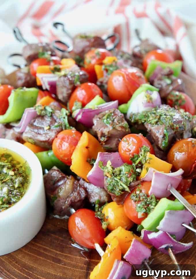 Steak and veggie skewers piled up on wood cutting board