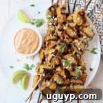 Grilled chicken skewers on plate with bowl of peanut sauce on the side