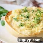 Half of a roasted spaghetti squash on plate topped with fresh chopped basil, ready for a healthy meal