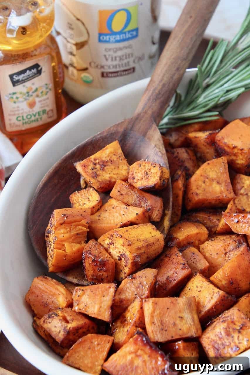 Honey roasted cubed sweet potatoes in a bowl with a wooden serving spoon