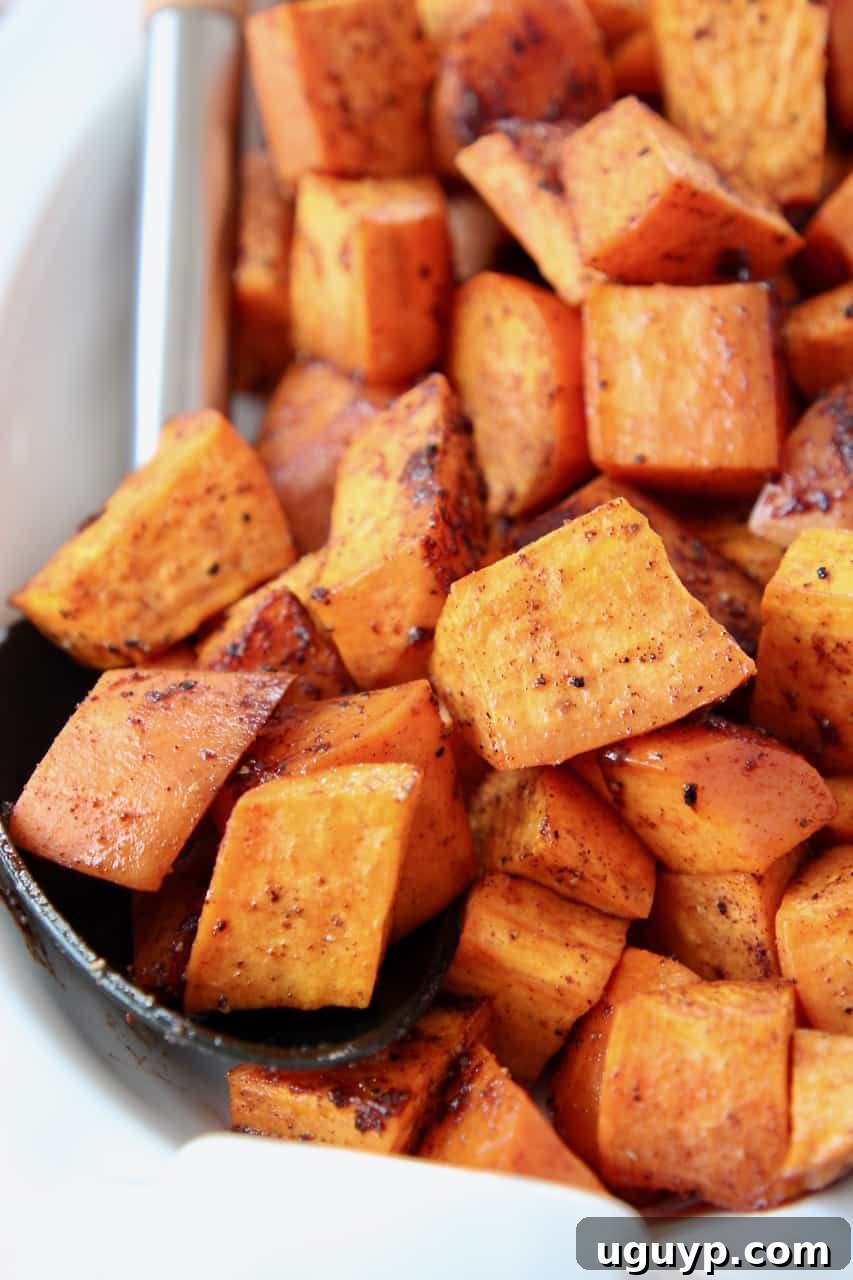 Roasted cubed sweet potatoes in a serving bowl with a wooden spoon, ready to be served