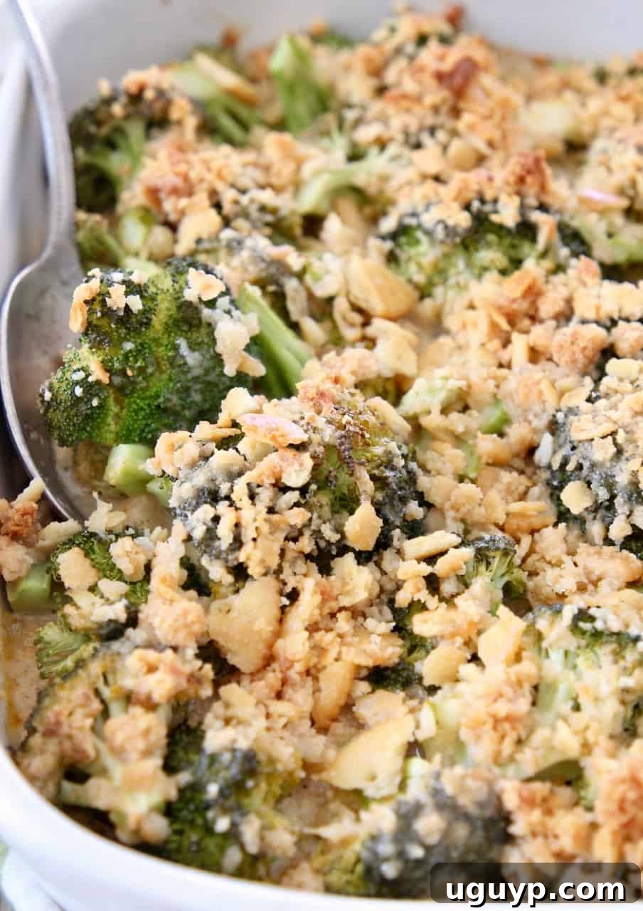 Delicious broccoli cheese casserole topped with golden Ritz crackers, with a serving spoon ready to scoop