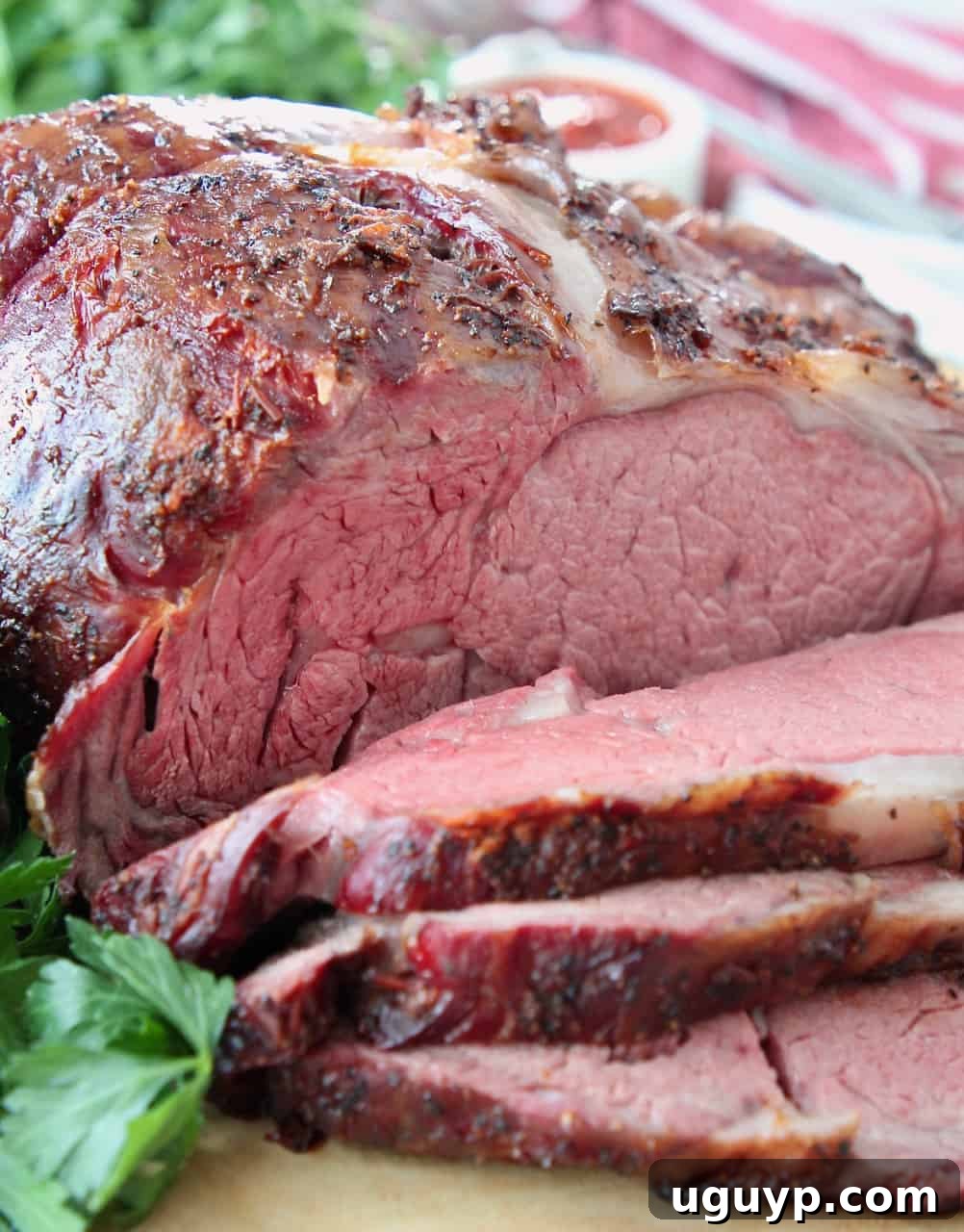 sliced smoked prime rib on wood cutting board, garnished with rosemary
