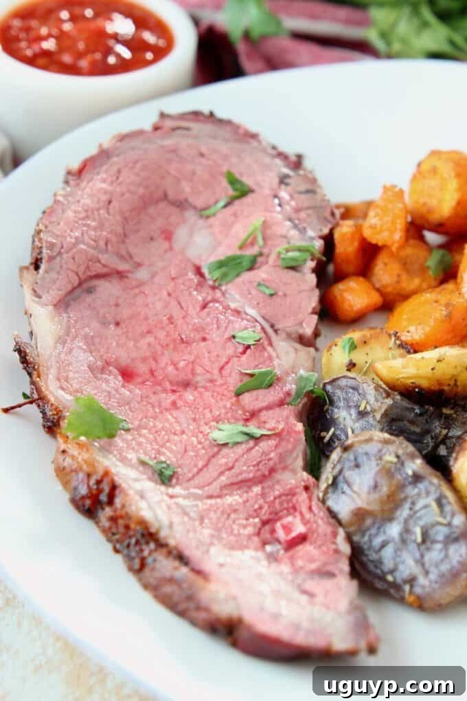 Slice of prime rib on plate with roasted vegetables, elegantly plated