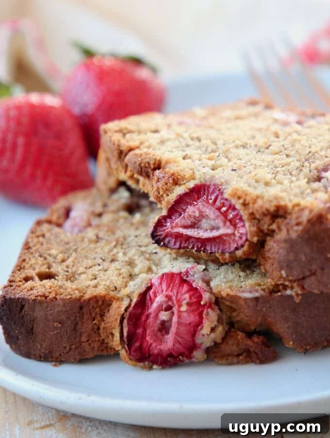 Thick slices of perfectly baked Gluten Free Strawberry Banana Bread arranged on a white plate, revealing its moist texture and flecks of fresh strawberries, promising a delightful treat.