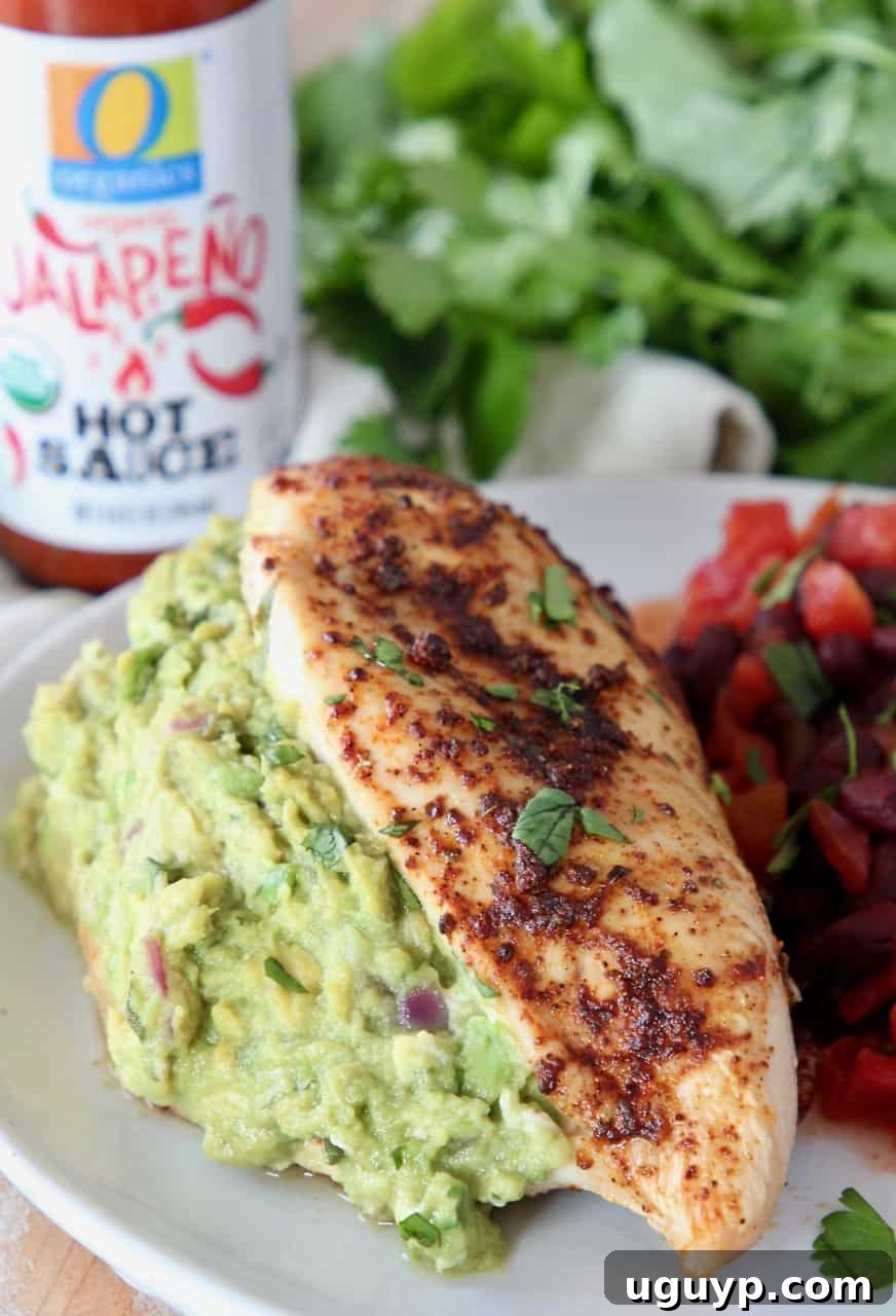 guacamole stuffed chicken breast on plate with black beans and roasted vegetables