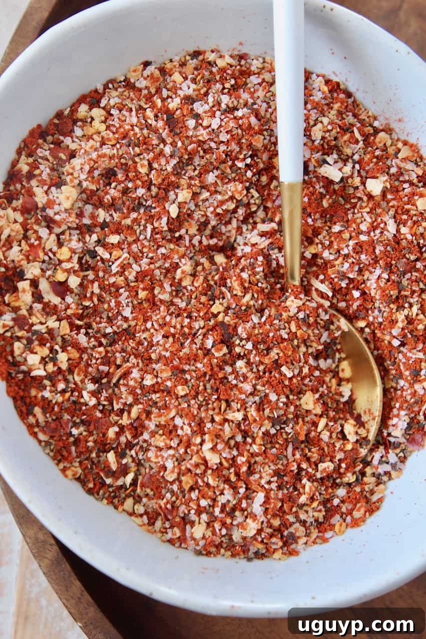 Overhead image of freshly prepared Montreal steak seasoning in a small bowl with a measuring spoon, ready for use.