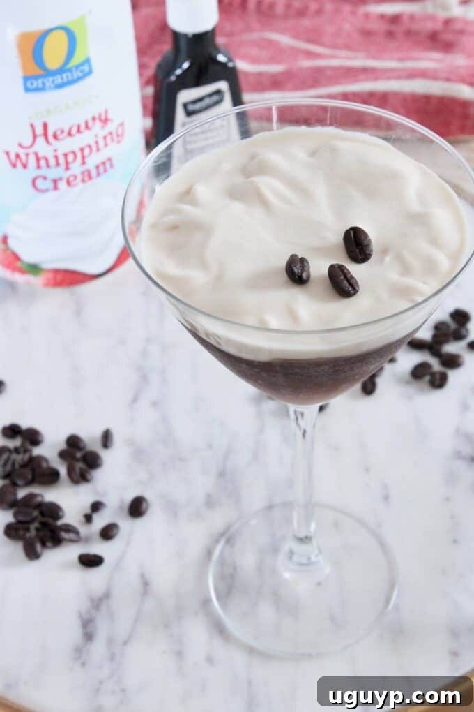 espresso martini topped with creamy vanilla whipped cream and coffee bean garnish in a martini glass