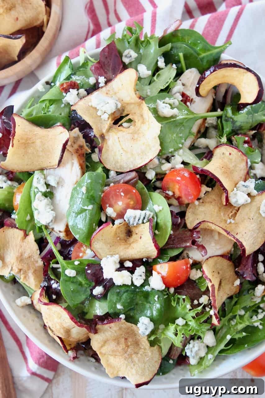 salad in bowl tossed with apple chips and gorgonzola cheese