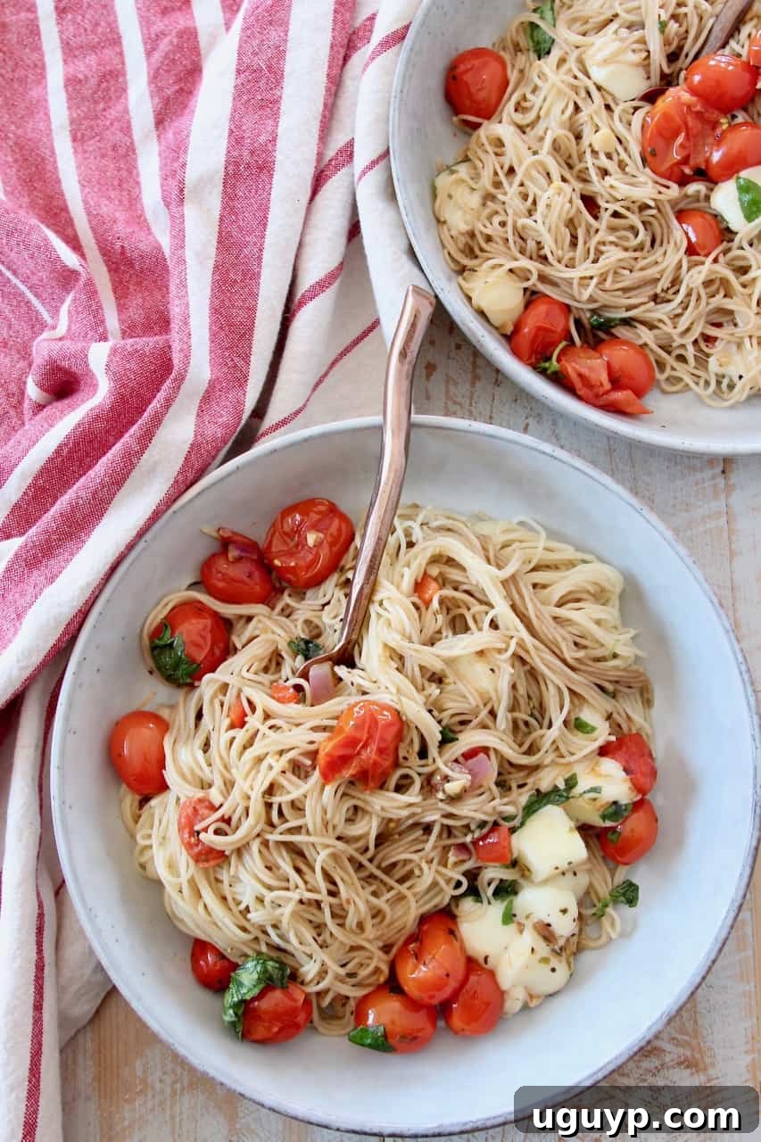 Two bowls of Caprese pasta with angel hair, cherry tomatoes, and mozzarella cubes, garnished with fresh basil, ready to eat.