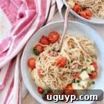 cooked angel hair pasta in bowl with cherry tomatoes, basil and mozzarella cheese