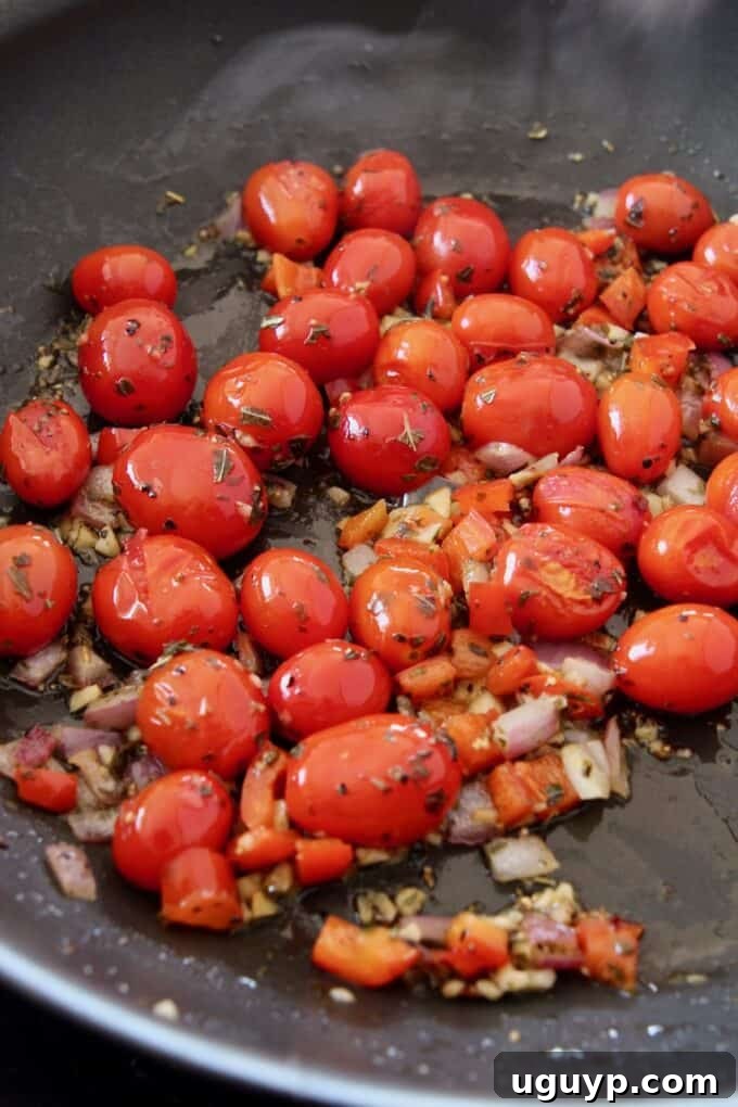 Burst cherry tomatoes mingled with sautéed onions, bell peppers, and garlic in a skillet, forming a vibrant, chunky sauce.