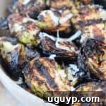 grilled brussels sprouts in bowl topped with grated parmesan cheese