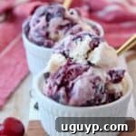 Scoops of cherry ice cream in a bowl with a gold spoon