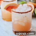 Paloma in glass with Tajin on the rim and grapefruit wedge on the edge of the glass