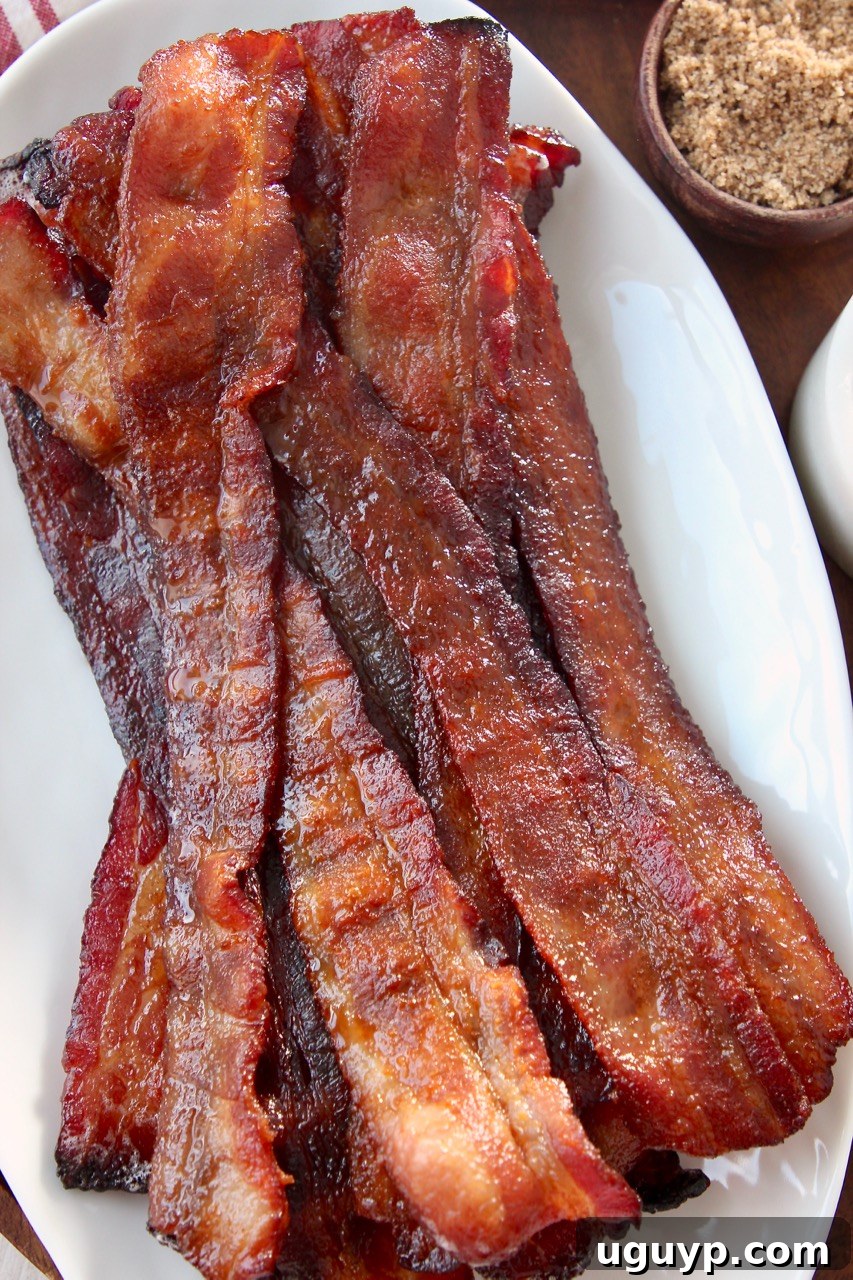 slices of cooked candied bacon on top of each other on white plate